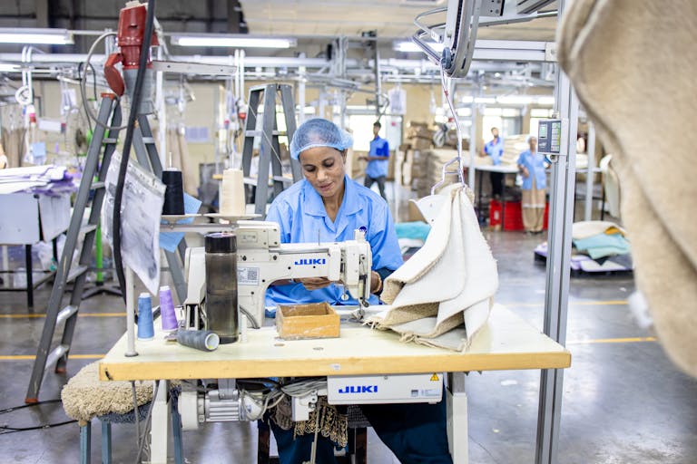 FLAIROC GHANA Textile factory worker sewing fabric using Juki machine in industrial setting. CETECH Ghana