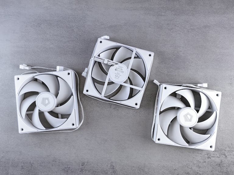 Three white computer cooling fans on a grey background, showcasing modern cooling equipment.